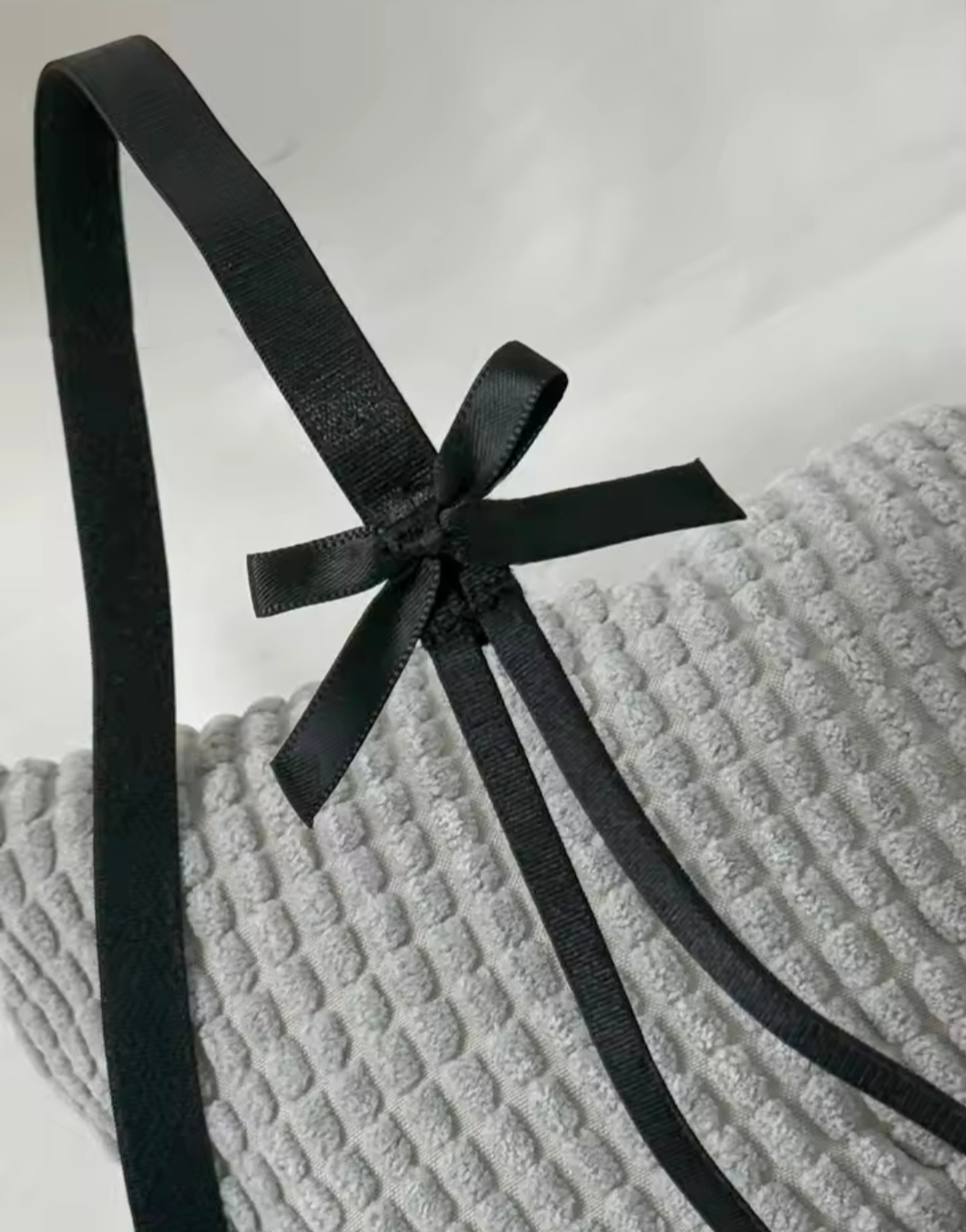 Black ribbon tied in a bow on a textured gray surface