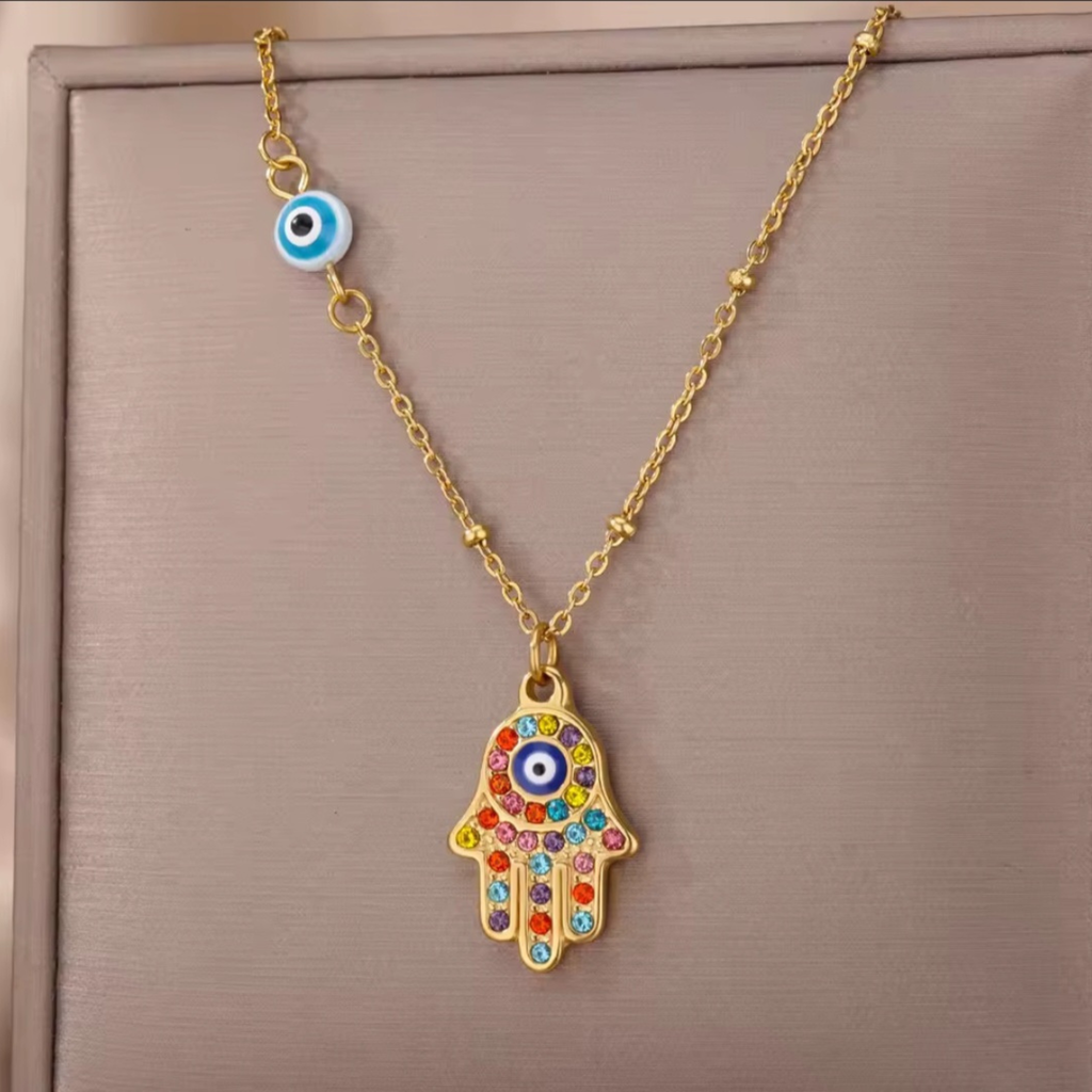 Necklace with a colorful Hamsa hand pendant and evil eye charm on a beige background