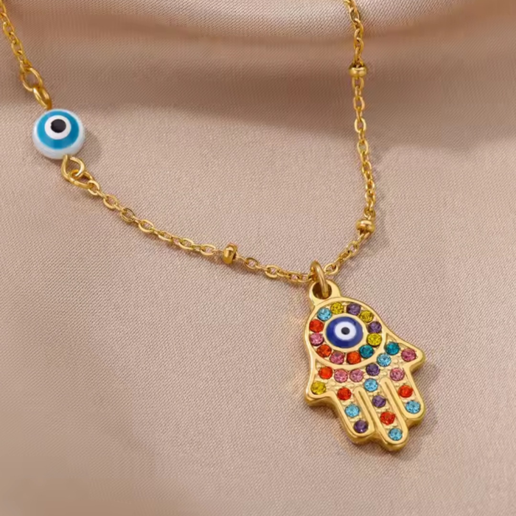 Necklace with a colorful Hamsa hand pendant and evil eye charm on a beige background