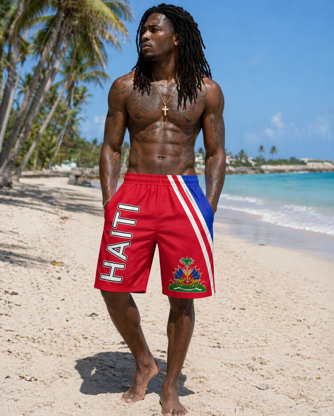 Man wearing red 'Haiti' shorts on a beach with palm trees and ocean in the background
