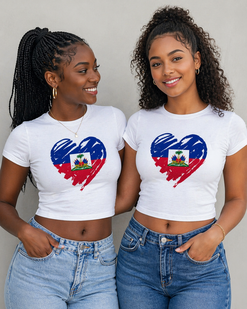 Two women wearing white t-shirts with a heart-shaped design featuring the Haitian flag, standing against a plain background.