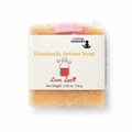 A packaged bar of handmade artisan soap labeled 'Love Spell' by Lakay Remedies, wrapped in clear plastic with a cream paper label, on a white background.
