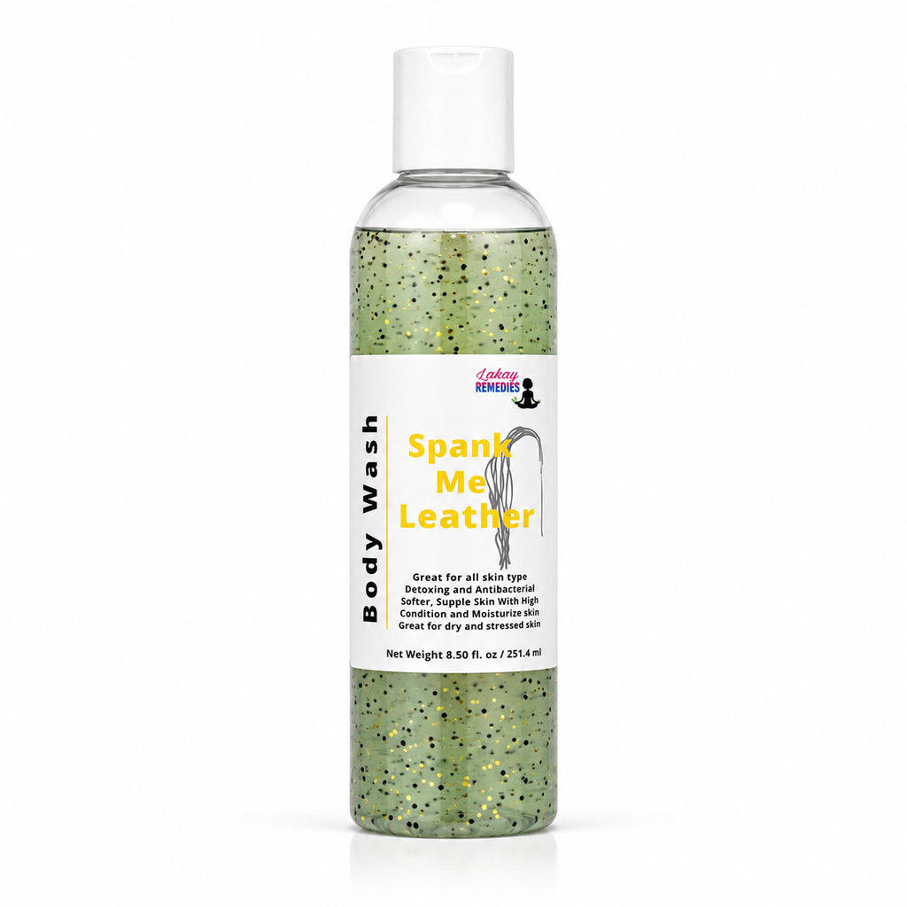 A clear plastic bottle of body wash with a white cap and a white label reading 'Body Wash' and 'Spank Me Leather' in yellow text. The liquid inside is green with black and gold jojoba beads.