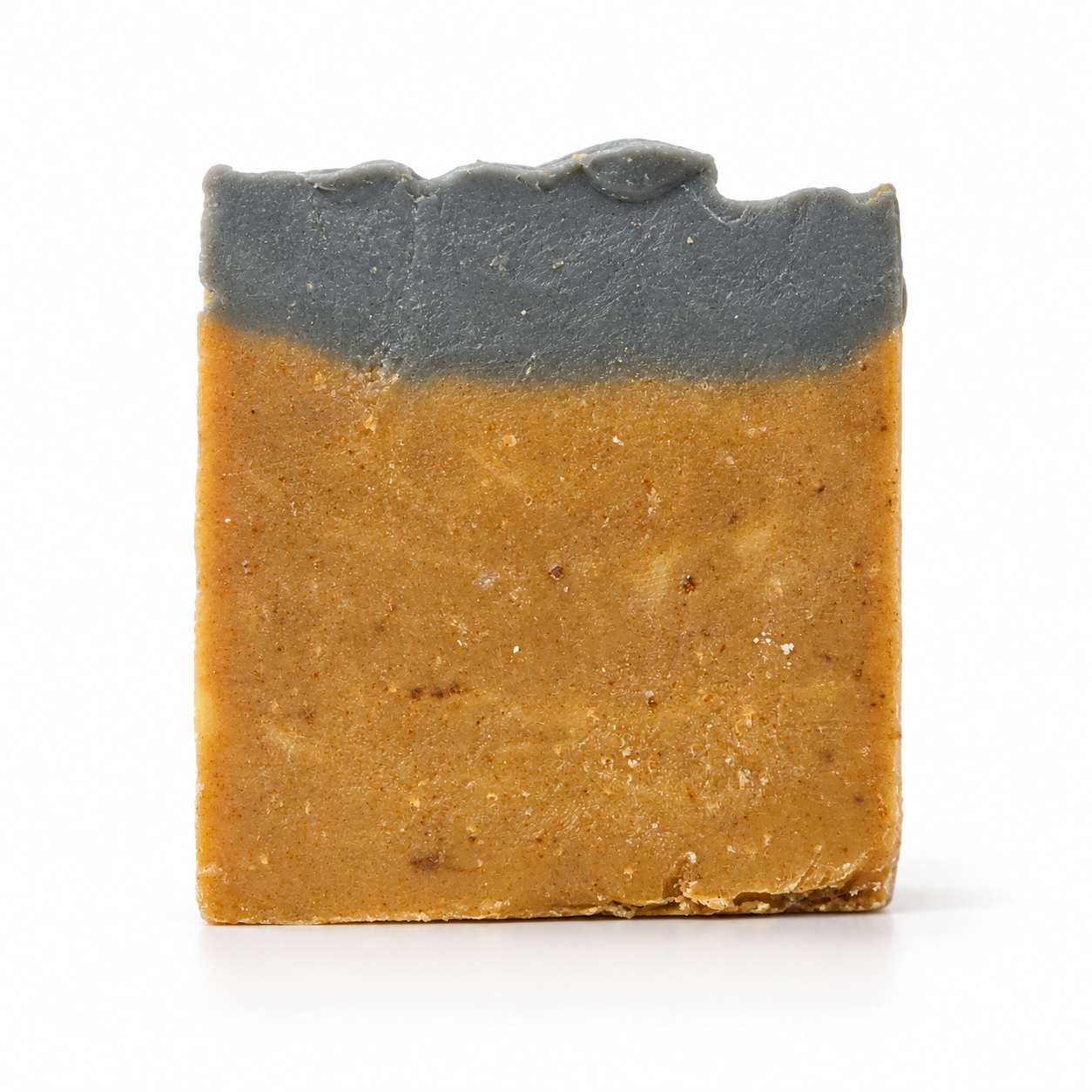 A rectangular bar of handmade soap with a two-tone design, featuring a dark charcoal gray top layer and a warm golden-brown textured bottom layer, set against a plain white background.