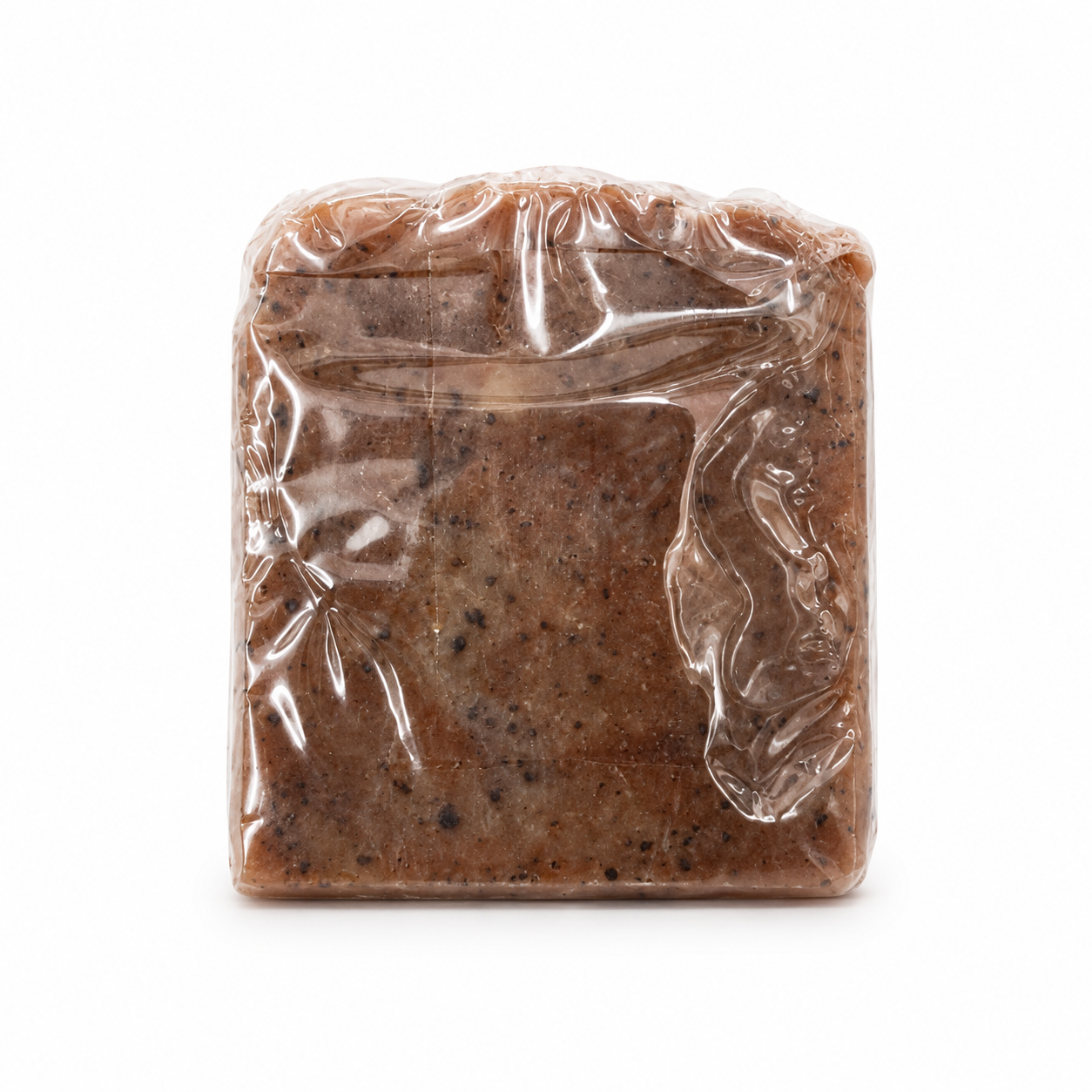 A square bar of brown soap wrapped in clear plastic, showing a speckled texture, isolated on a white background.