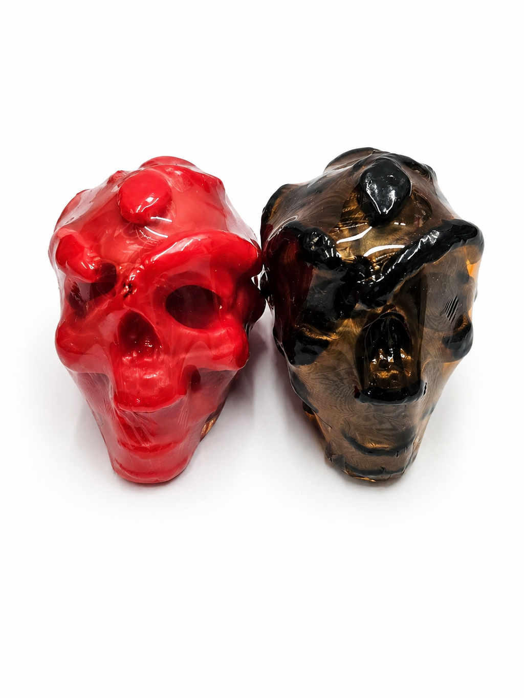Two red and black skull-shaped candle on a white background