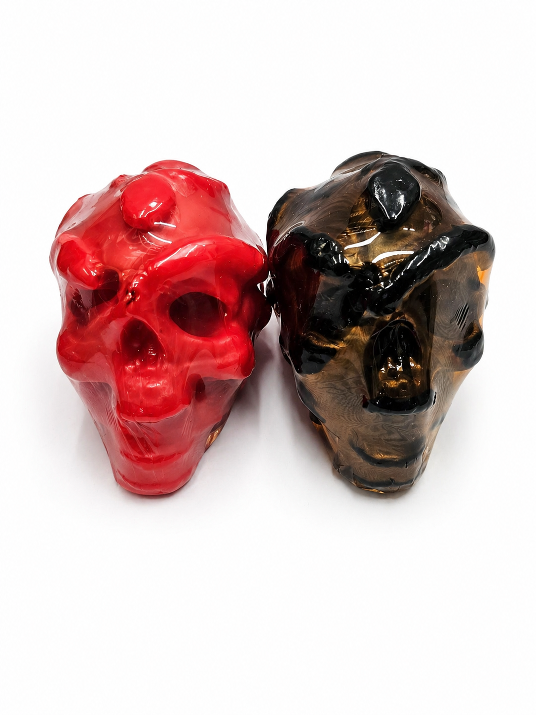 Two red and black skull-shaped candle on a white background