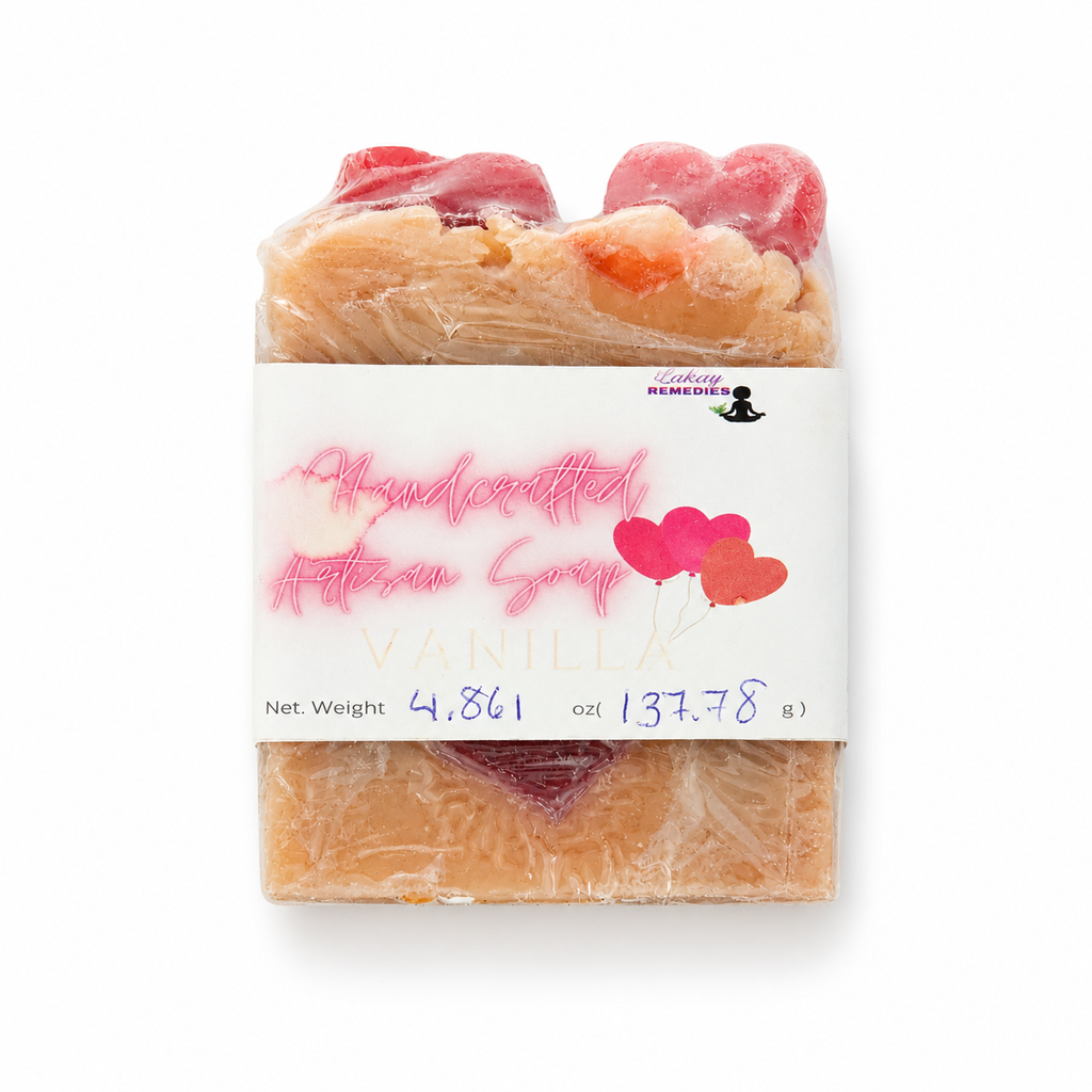 A handmade artisan soap bar wrapped in clear plastic with a white paper label. The label reads 'Handcrafted Artisan Soap VANILLA' with pink script and heart graphics.