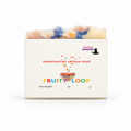 A boxed handmade artisan soap bar with colorful soap pieces visible at the top, wrapped in clear plastic and presented in a white box labeled 'Fruity Loop' by Lucky Remedies.