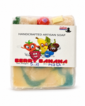 A packaged handmade artisan soap bar labeled 'Berry Banana' by Lucky Remedies, wrapped in clear plastic with a white paper label featuring colorful cartoon fruit characters.