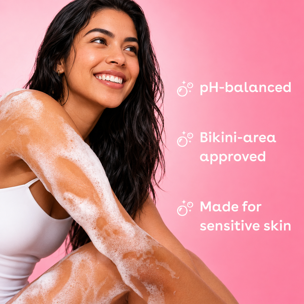A smiling woman with white body foam on her arm poses against a pink background with text reading 'pH-balanced', 'Bikini-area approved', and 'Made for sensitive skin'.
