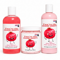 Three skincare products from Lakay Remedies on a white background: a pink bottle of Aloe Shea Butter Silk Amino Acids body lotion, a pink jar of body scrub, and a pink bottle labeled 'You're the POMME-DIGGITY' body wash.