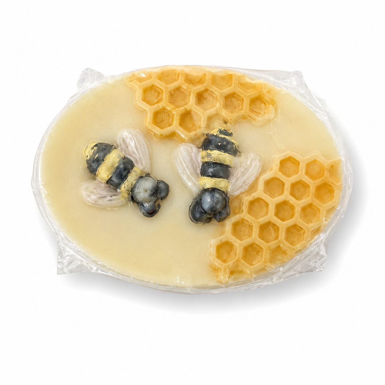 A round decorative soap bar wrapped in clear plastic, featuring a pale yellow base with embossed honeycomb patterns and two sculpted bumblebee figures on a white background.