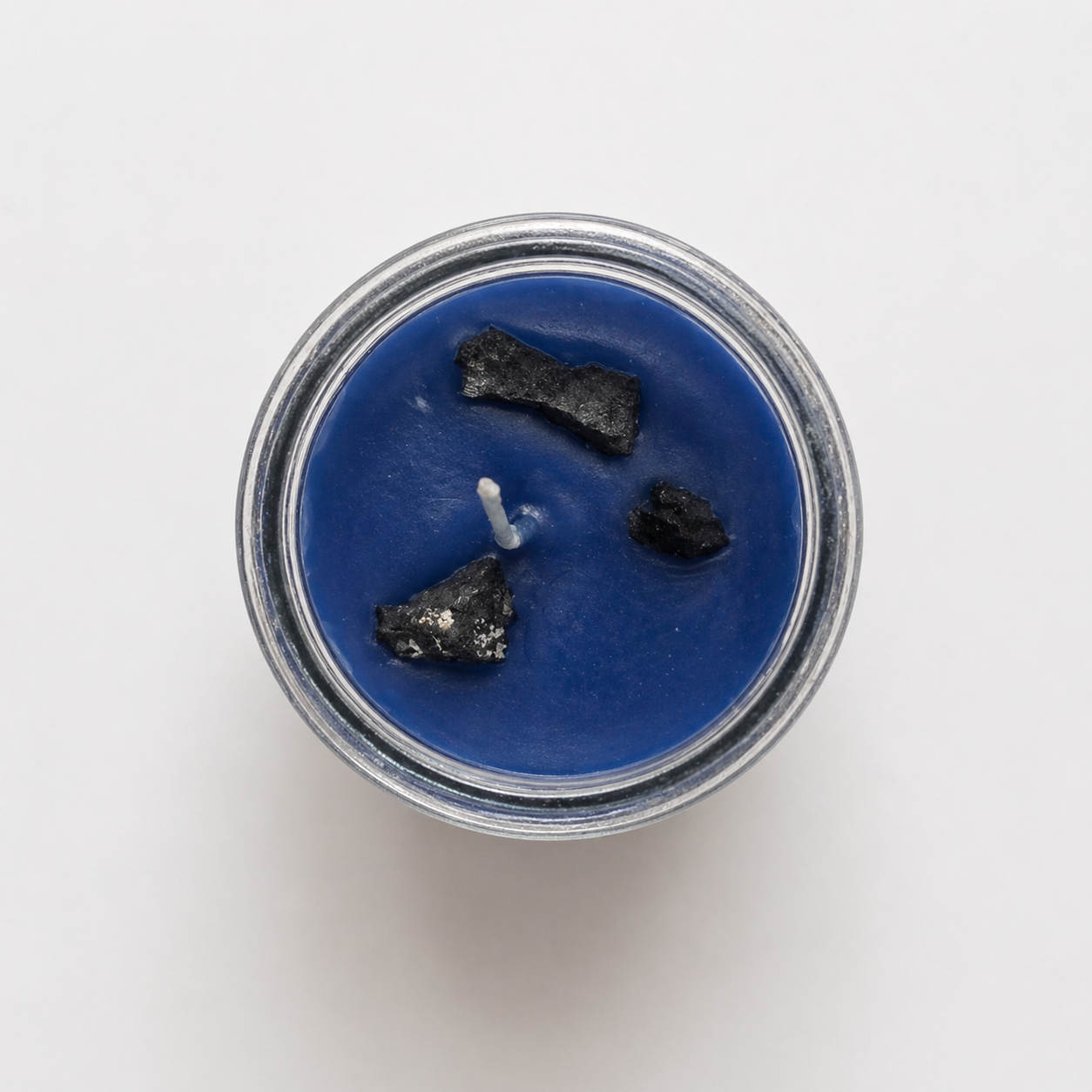 Blue candle with white wicks in a glass jar on a white background