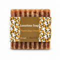 A single bar of Luxurious Soap 'Pumpkin Ginger Strudel' soap, showing its textured, brown, sugar-coated surface, wrapped in a brown paper label with orange and white camouflage patterns.