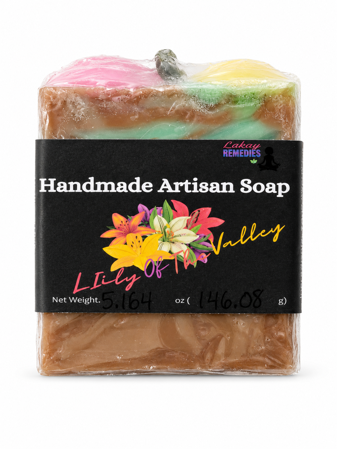 A handmade artisan soap bar wrapped in clear plastic, featuring a black paper label with colorful floral graphics and the text 'Handmade Artisan Soap' and 'Lily of the Valley.' The soap itself has layered pastel pink, mint green, and yellow on top of a warm brown base.