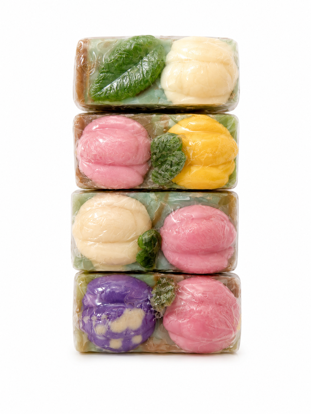 Four stacked rectangular bars of soap in clear wrapping, each decorated with colorful molded details including pink, yellow, green, purple, and cream shapes, shown on a white background.