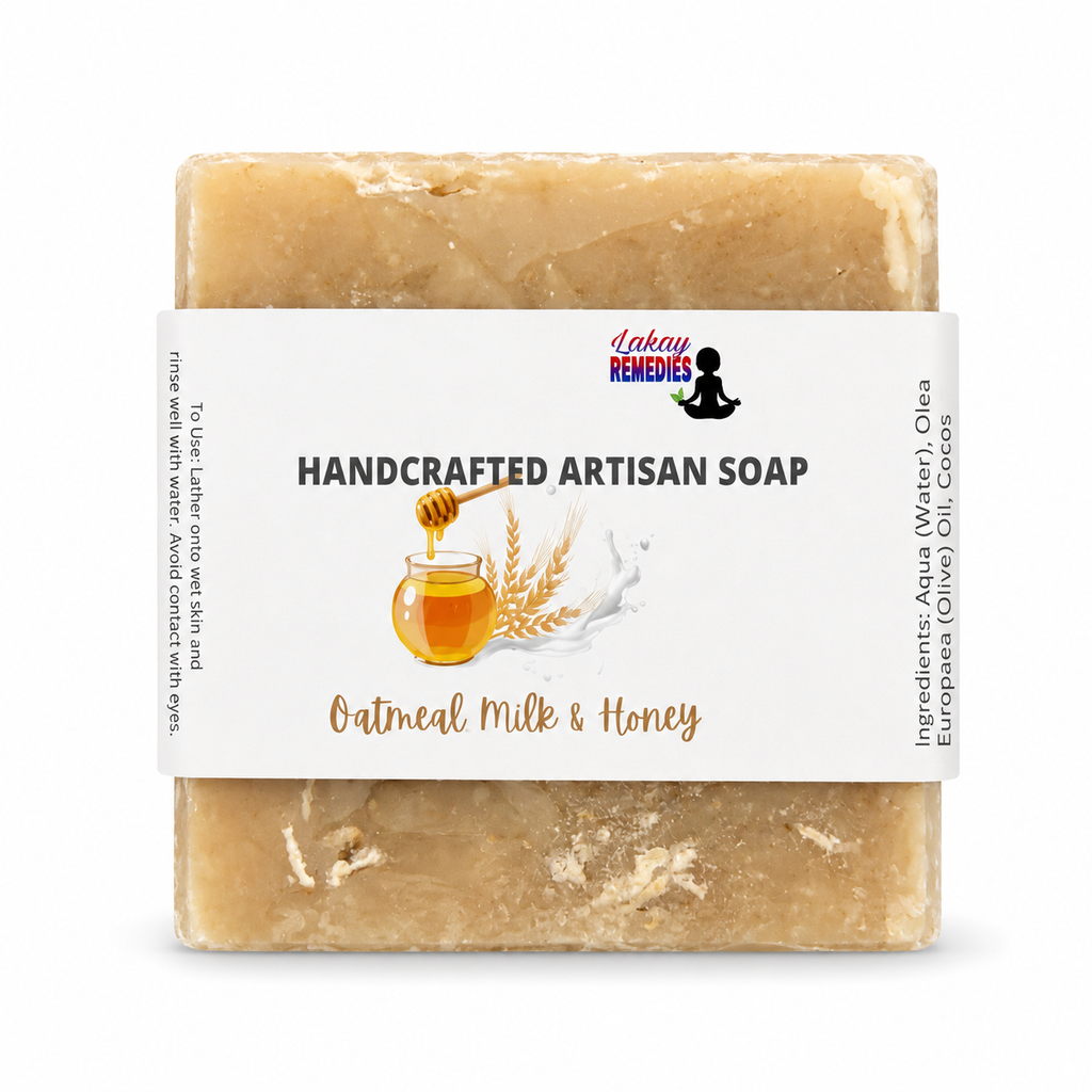 A rectangular bar of handmade artisan soap in a light tan, oatmeal-colored shade, wrapped in a white paper label that reads 'HANDCRAFTED ARTISAN SOAP' and 'Oatmeal Milk & Honey'. The brand 'Lakay Remedies' is visible on the label.