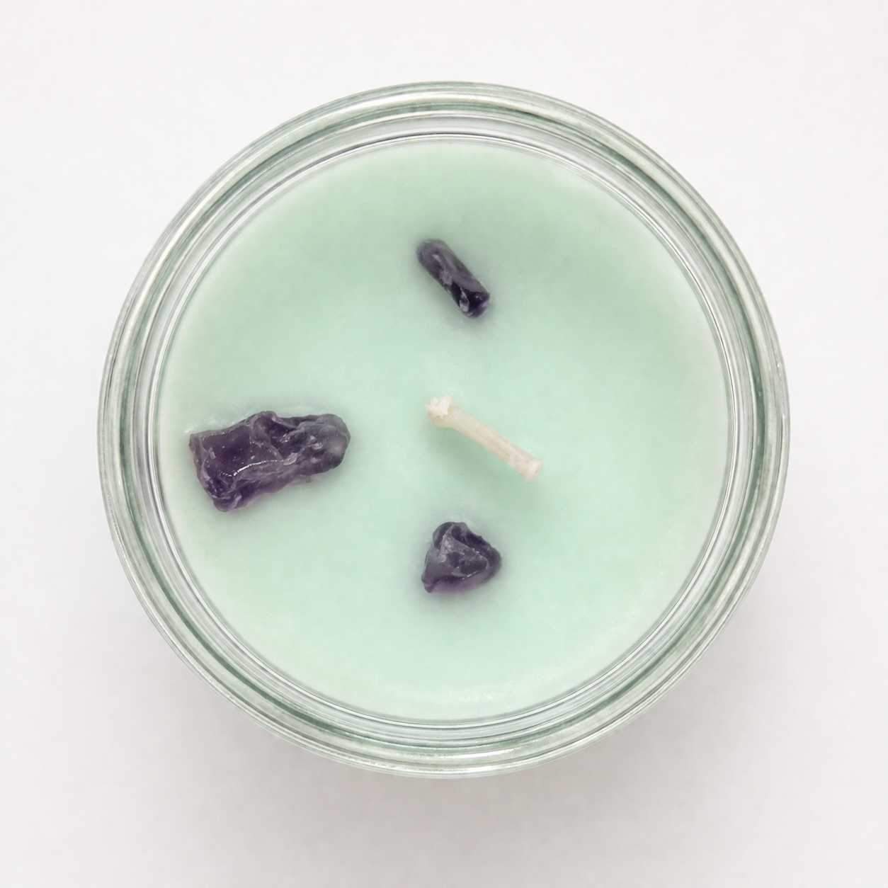 Candle in a glass jar with a white wick on a light gray background