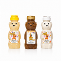 Three honey bear-shaped body care bottles on a white background: a yellow cap Honey Bear body wash, a gold cap Honey Bear body soap, and a white cap Honey Bear body lotion.