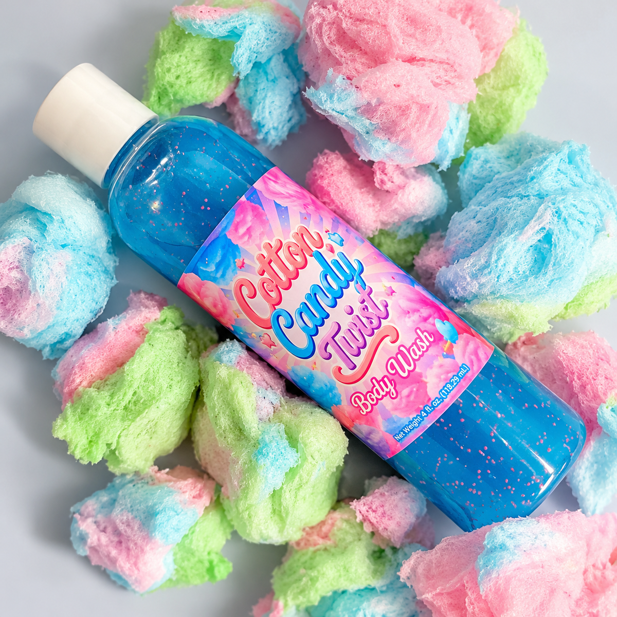 A bottle of body wash with blue gel inside, featuring a white cap and a blue label with pink and white text that reads 'Creamy Body Wash' and 'Cotton Candy Twist'.